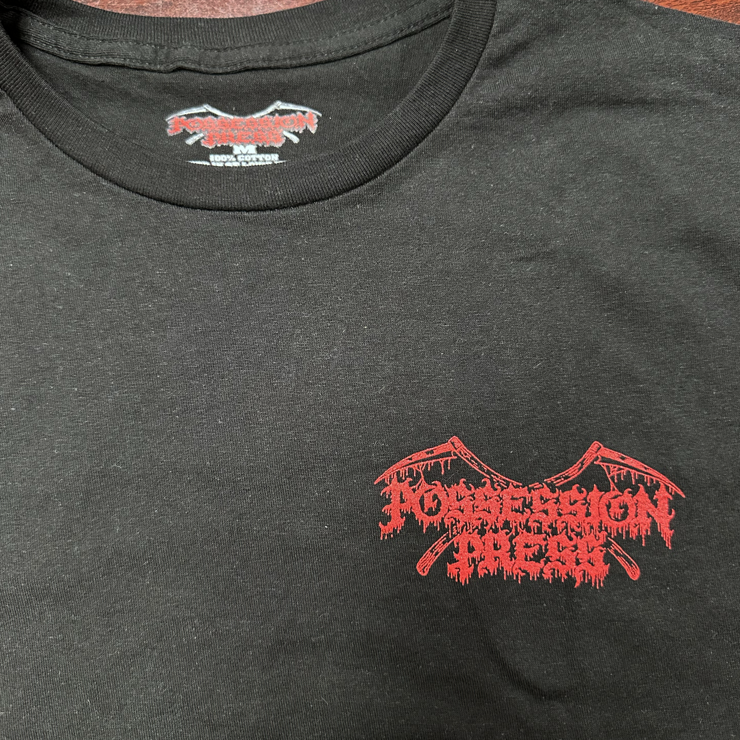 Black t-shirt with red graphic design brand logo on left chest 