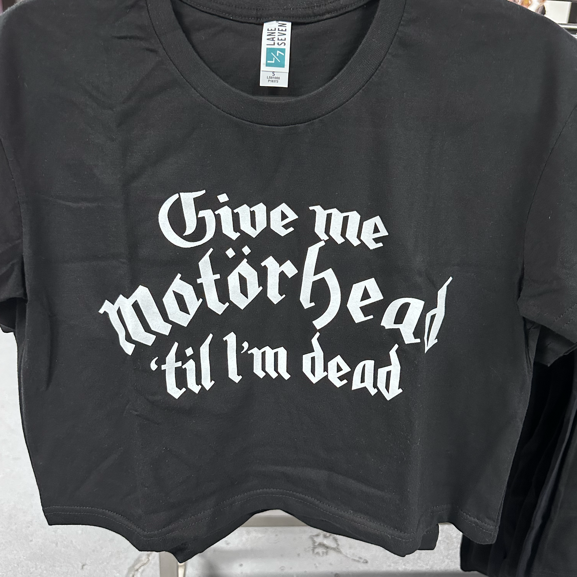 Black t-shirt with white text 'Give me Motorhead til I'm dead' on a gray background