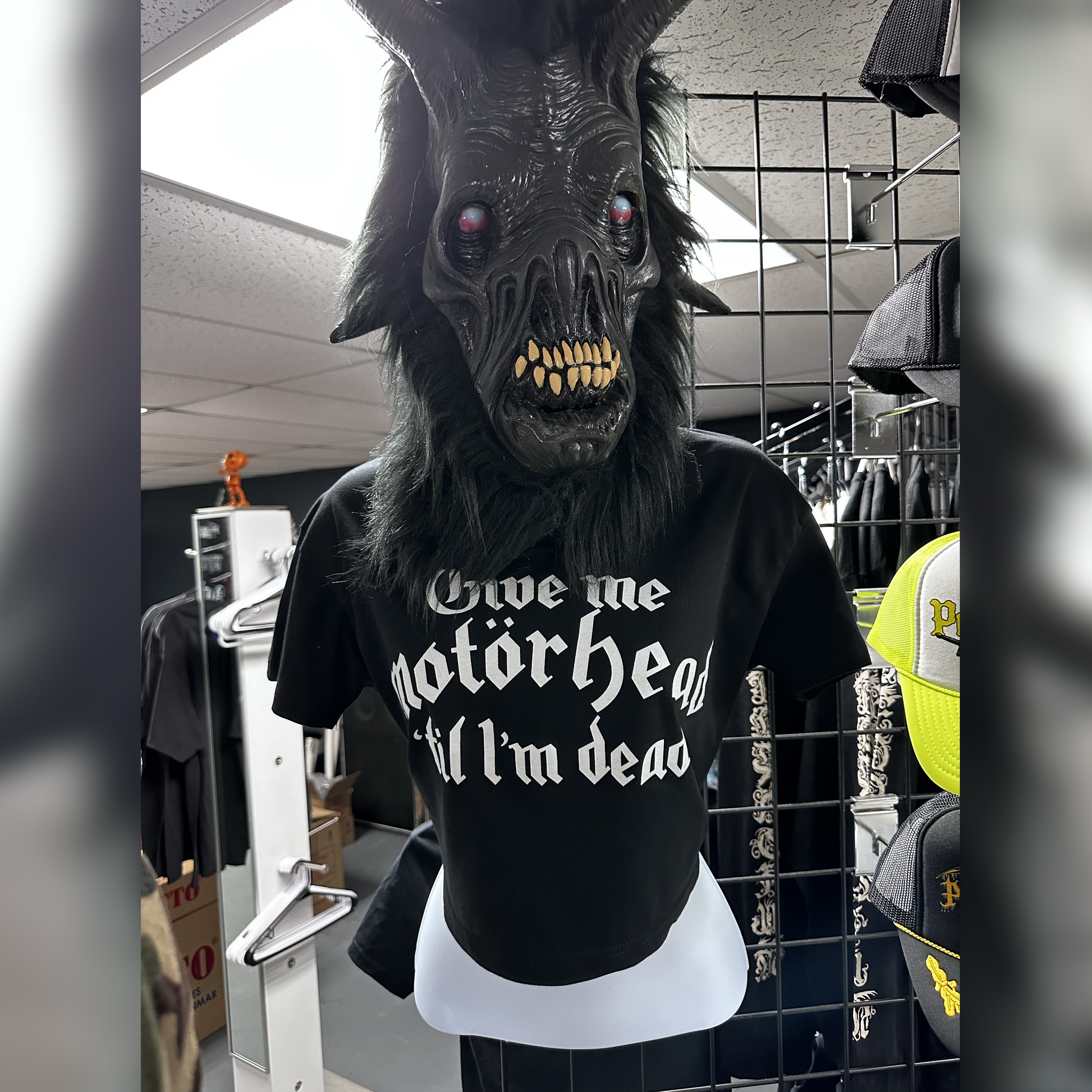 Mannequin wearing a dark mask and black t-shirt with white text in a store setting