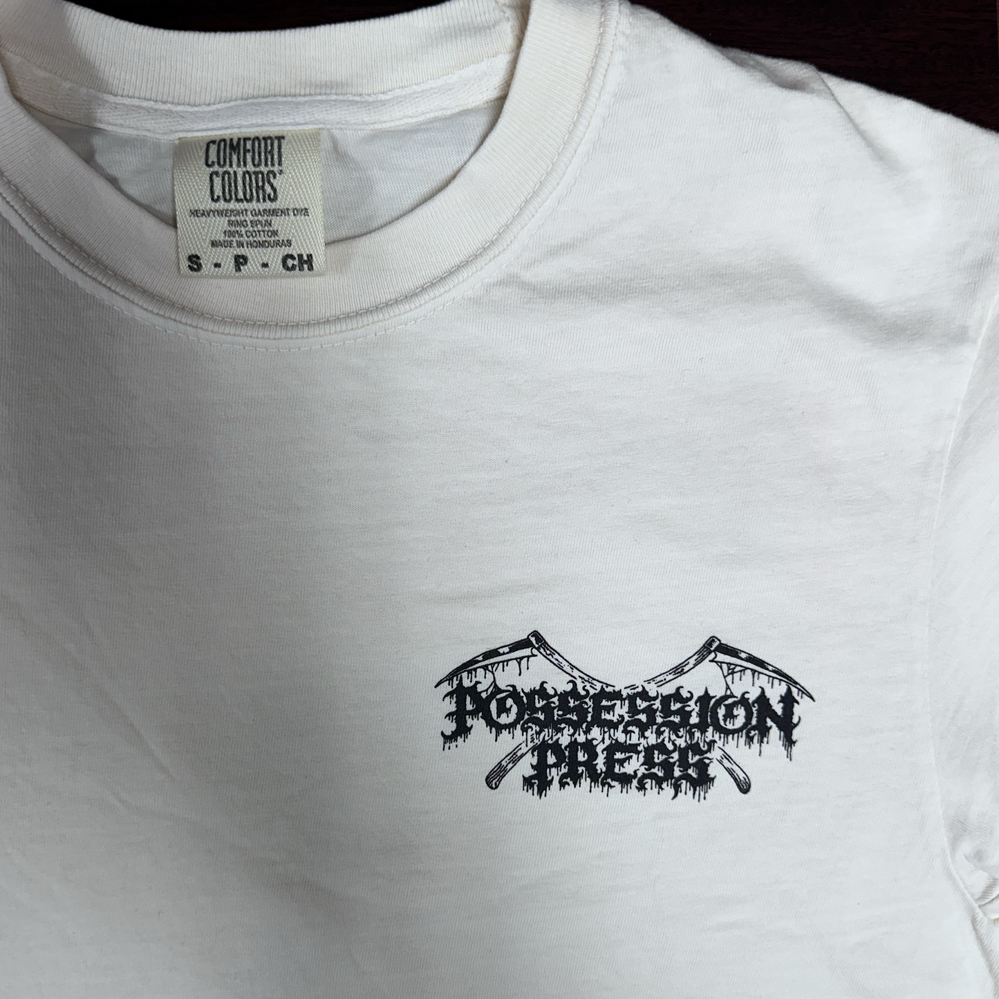 Ivory t-shirt with black graphic design and 'Comfort Colors' label on a dark surface