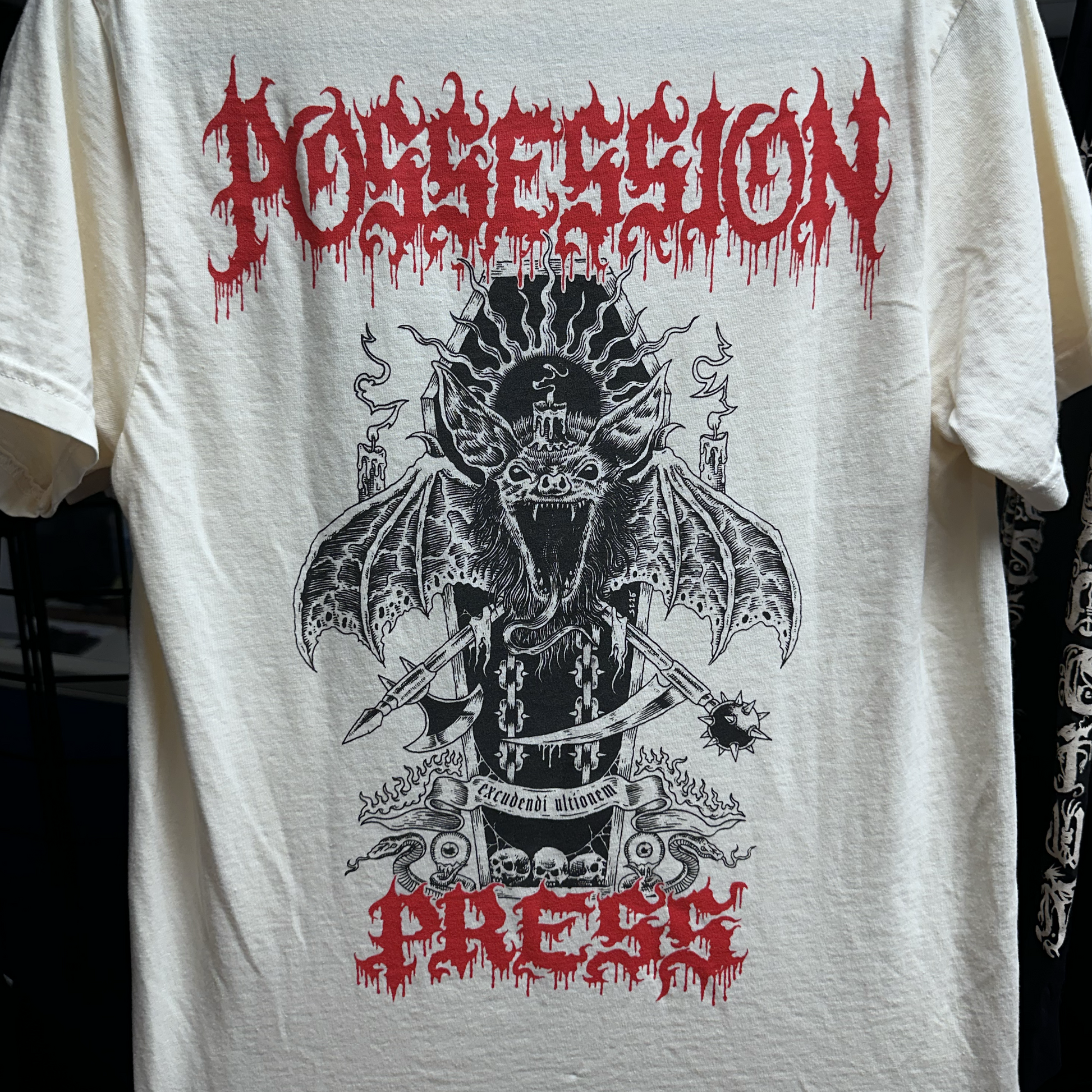 Ivory t-shirt with black and red graphic design featuring a bat-like creature and text on a white background.