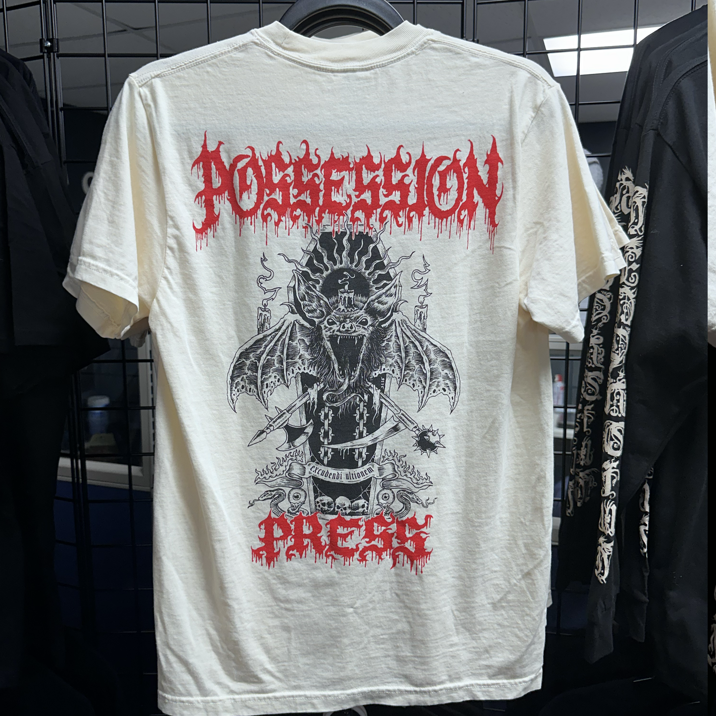 White t-shirt with black and red graphic design on a rack
