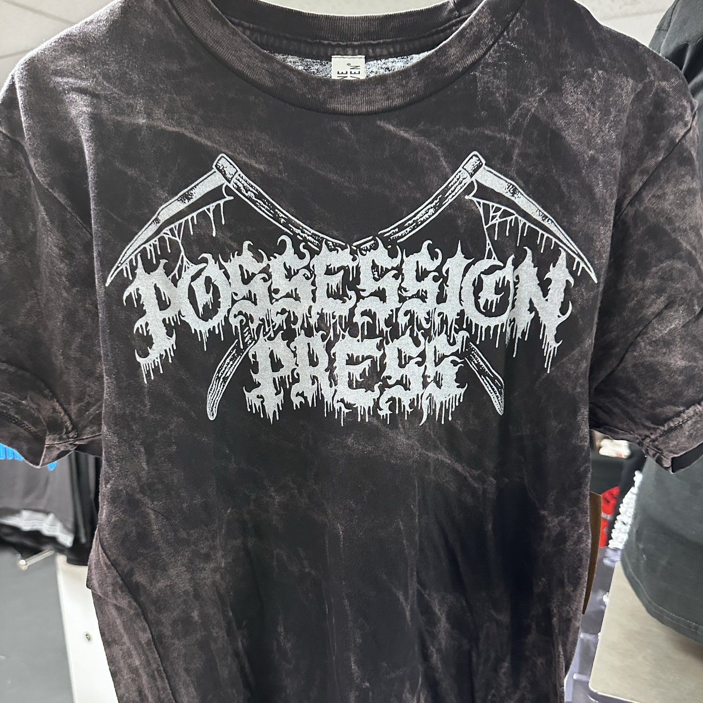 Black tie-dye t-shirt with white graphic design on a clothing rack.