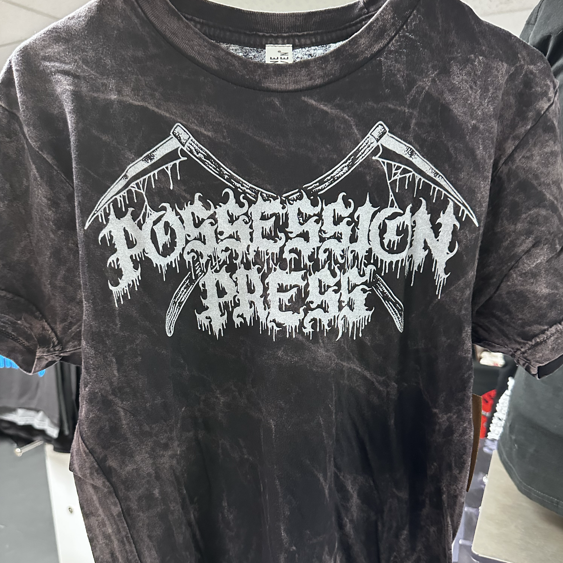Black tie-dye t-shirt with white graphic design on a clothing rack.